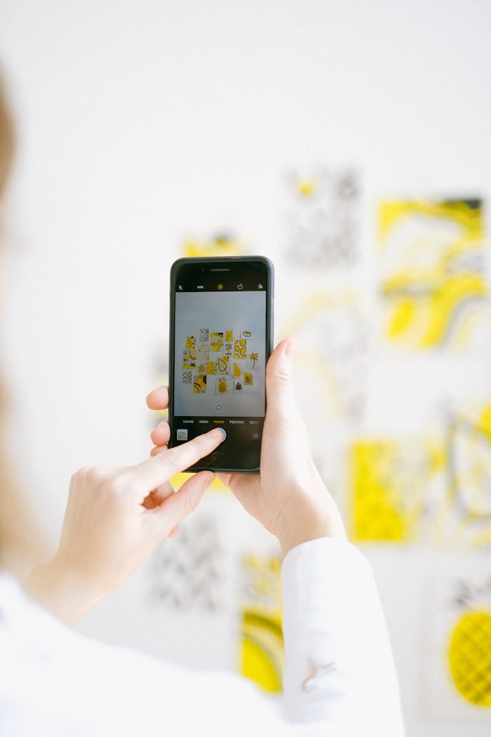 about-img Person photographing colorful artwork with a smartphone in bright light.